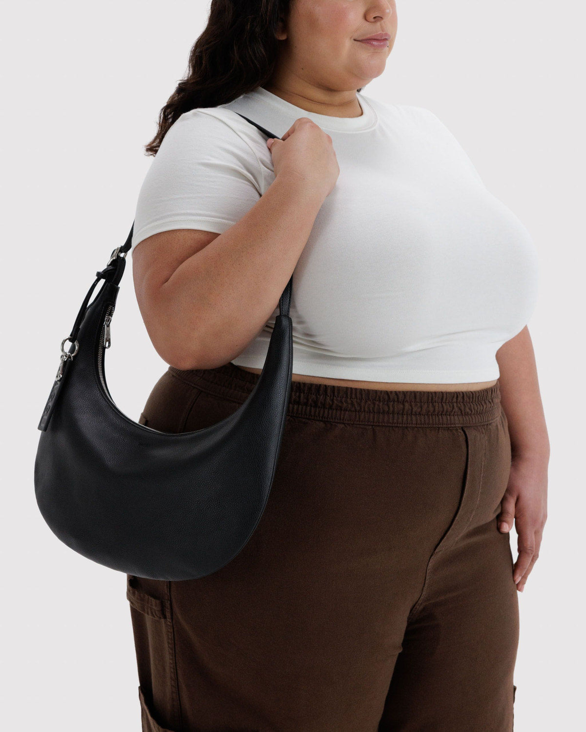 Medium crescent hobo bag in black recycled leather, worn crossbody with long strap