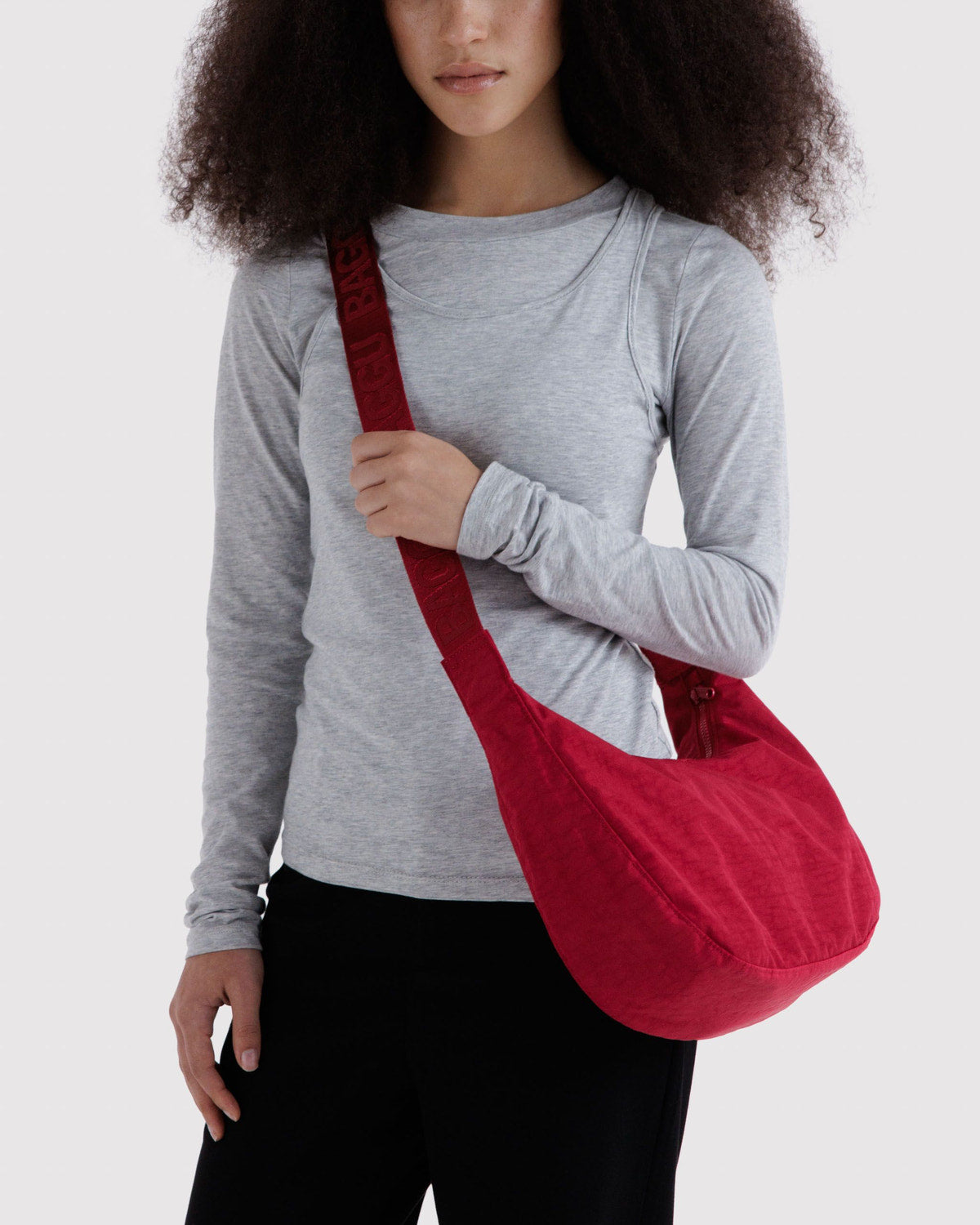 Medium nylon crescent bag, deep red, worn crossbody with adjustable strap