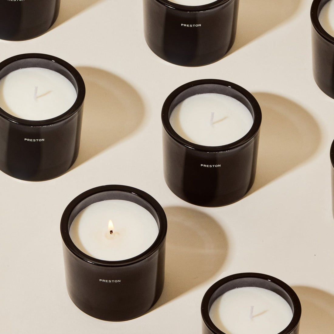 Set of black leather candles with white wax, one flame visible