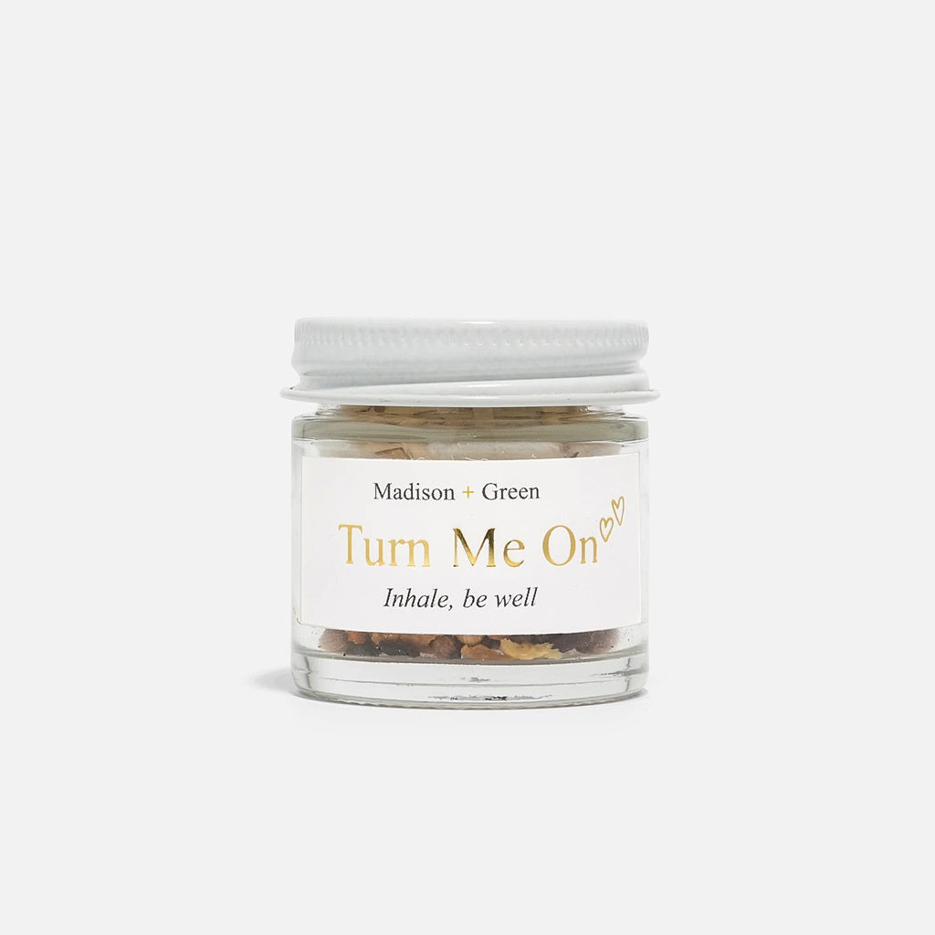 Aromatherapy inhaler jar labeled Turn Me On with white screw lid