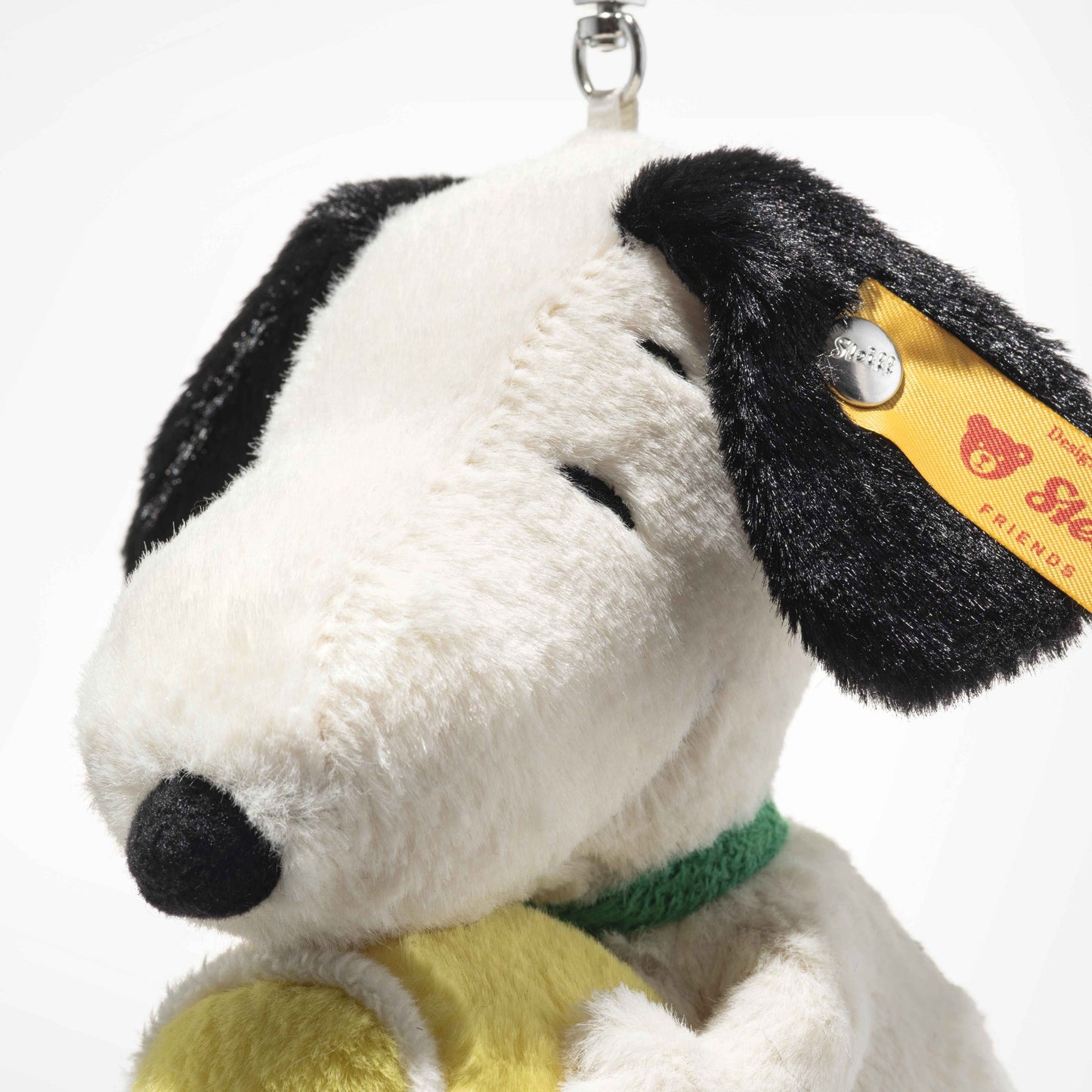 Plush Snoopy-style keychain close-up, black ear and tag with metal clip