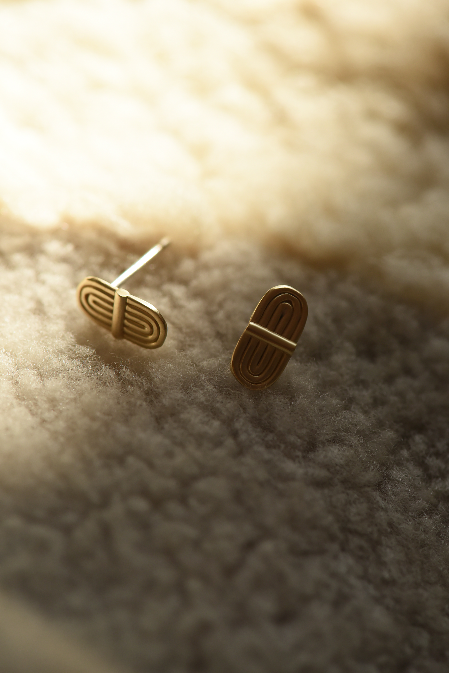 Pair of gold-tone double-arc brass stud earrings with curved bar fronts