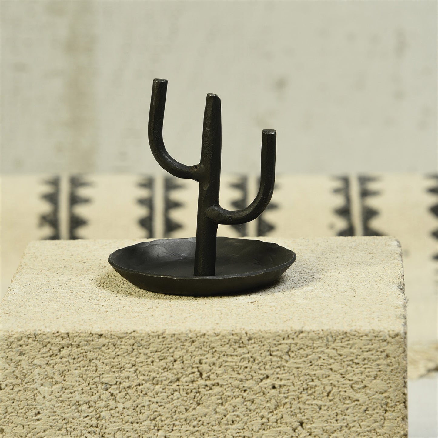 Black cactus-shaped ring holder with three prongs on a round base