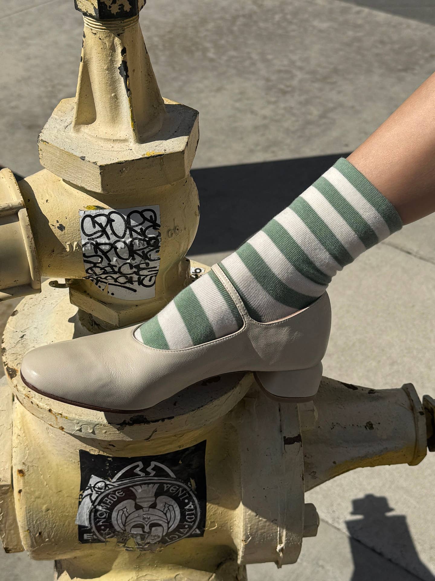 Green-and-white striped crew socks shown on feet with white shoes.