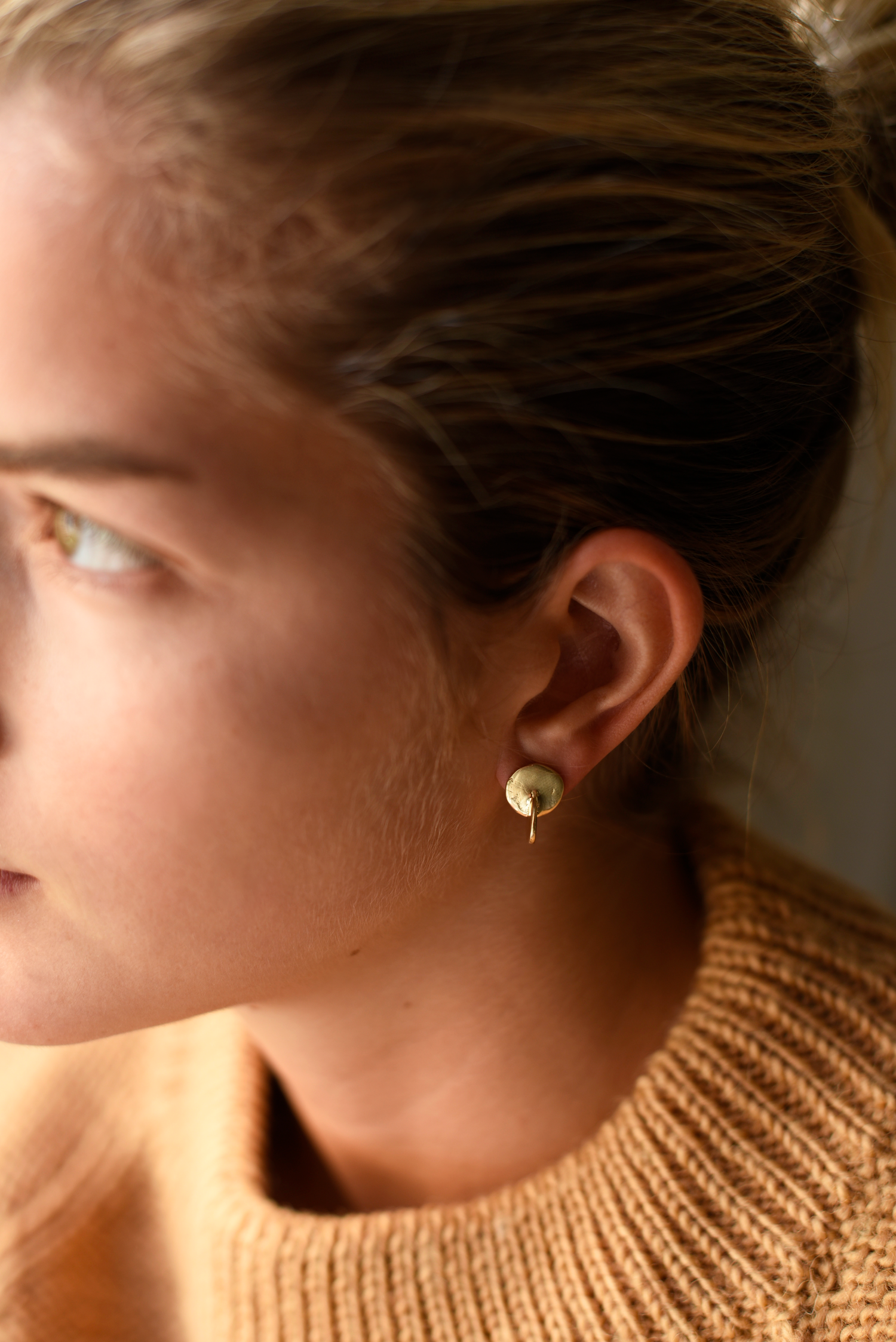 Brass round disc stud earrings with interlocking backplate, gold-tone, on ear
