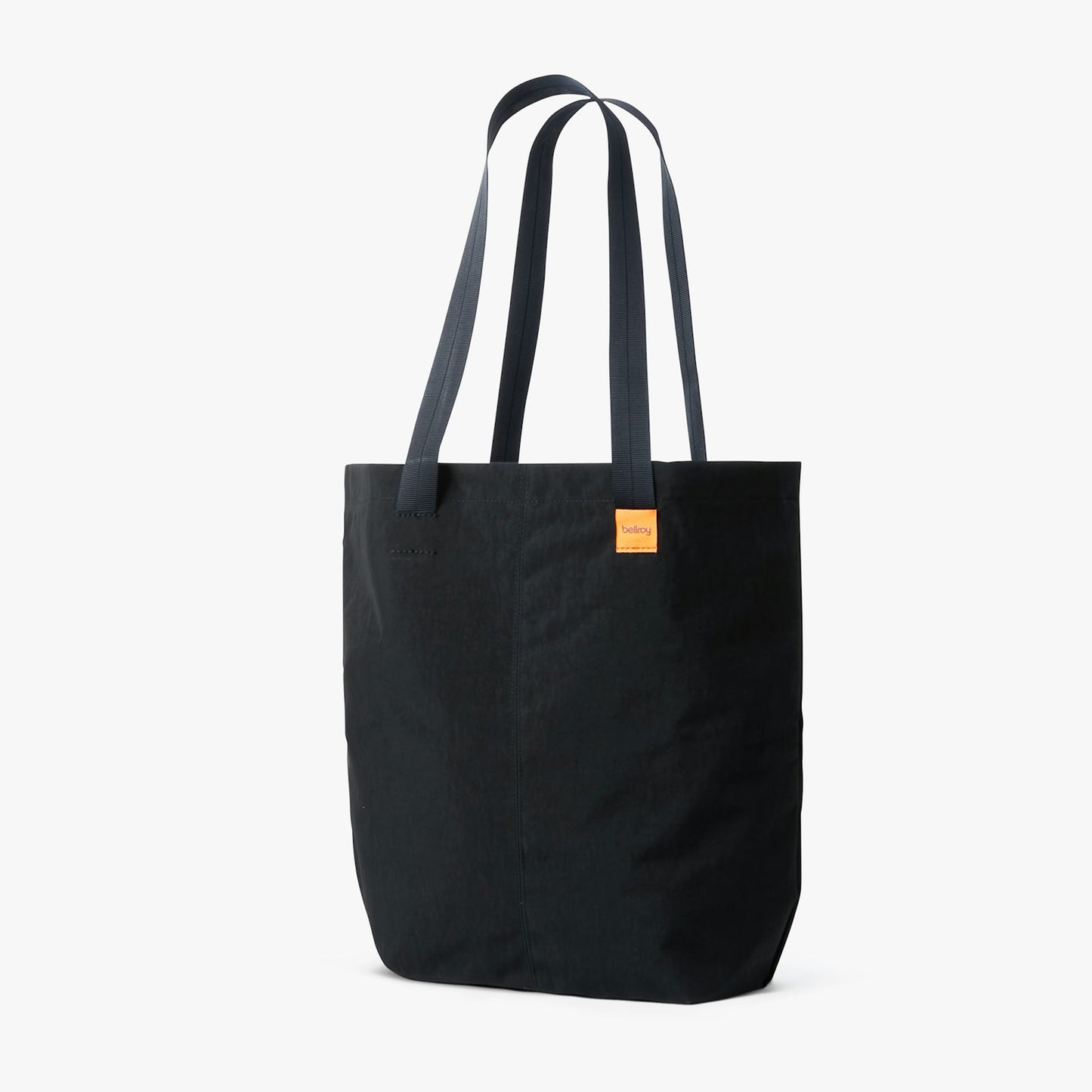City tote bag in dark black with two long handles and front label patch.