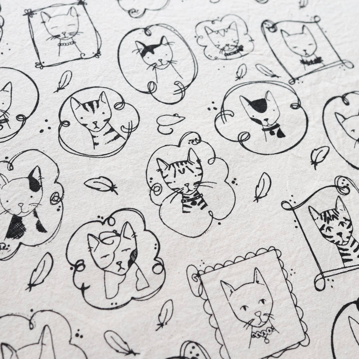 Close-up of cat kitchen tea towel pattern with black cat faces, paws, and leaves