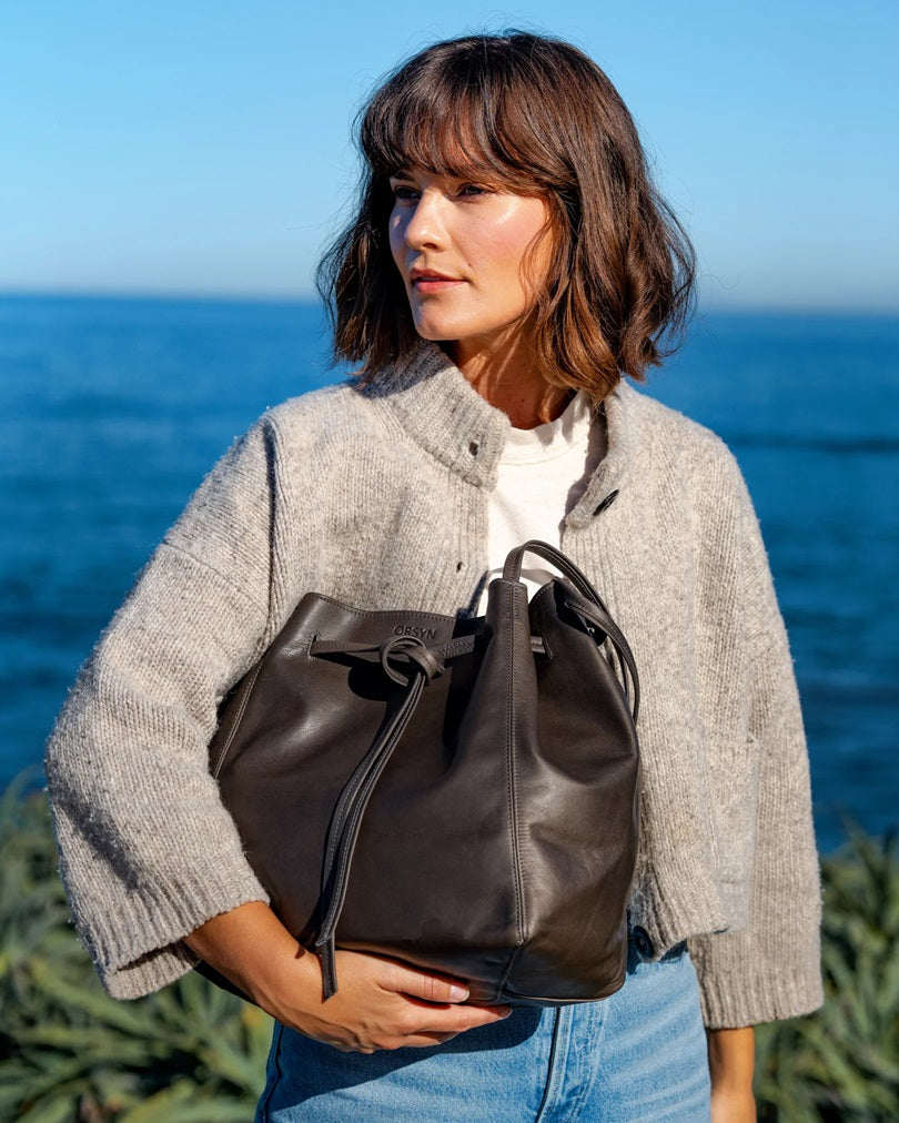 Dark leather tote bag with drawstring top and braided handles