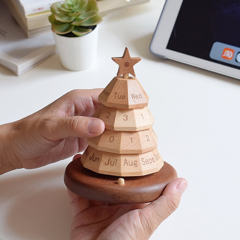 Wooden Christmas tree calendar held in hand, star topper and labeled blocks on round base