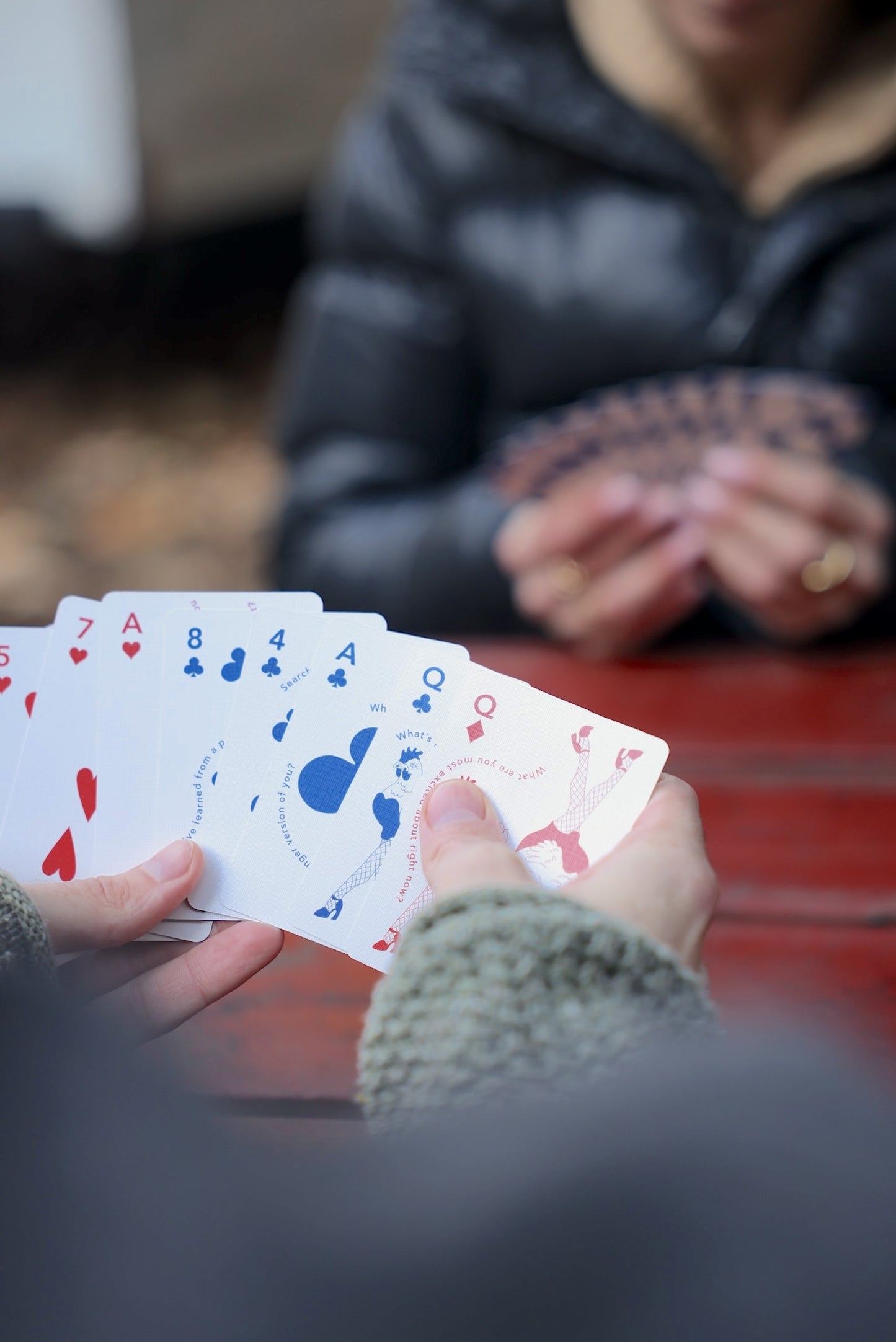 Playing card deck in hands, cards showing hearts, spades, and numbers