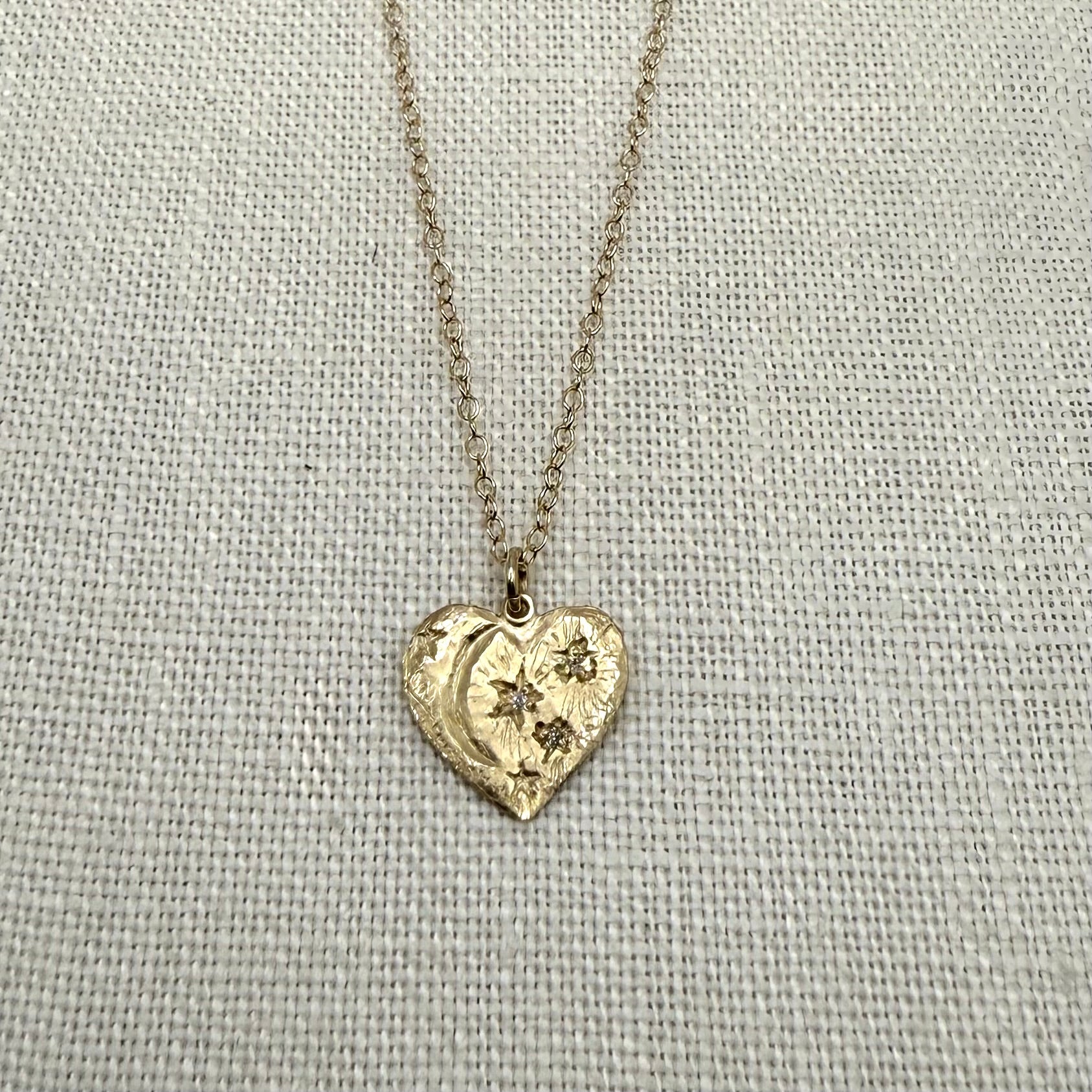 Gold heart pendant necklace with starburst details and fine chain