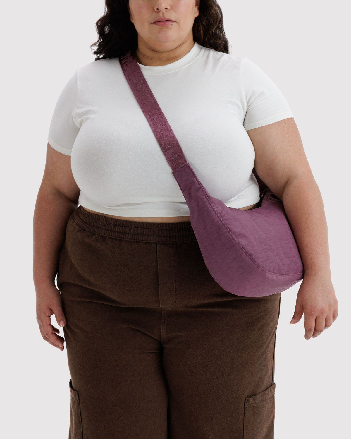 Medium nylon crescent bag in plum purple worn crossbody with patterned strap