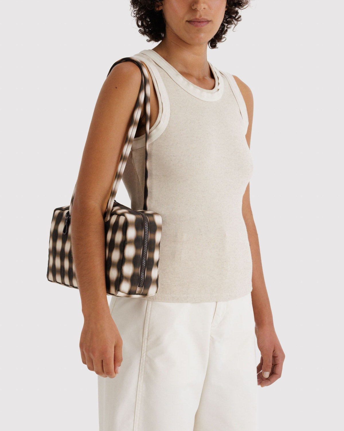 Brown-and-cream check nylon bowler bag with top zipper and short handles, worn