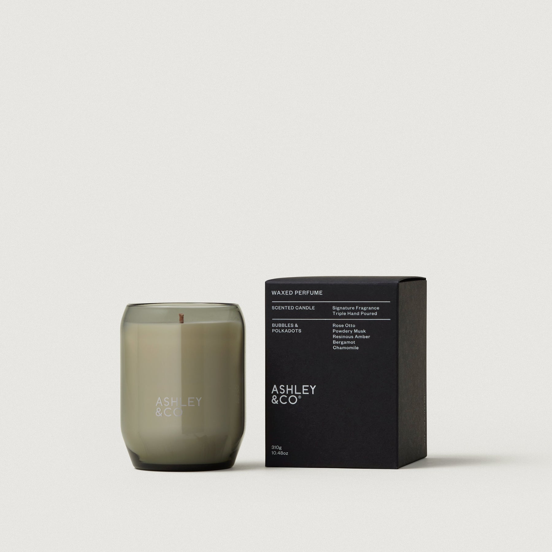 Waxed perfume candle in smoky olive glass jar with lit wick and black scent box