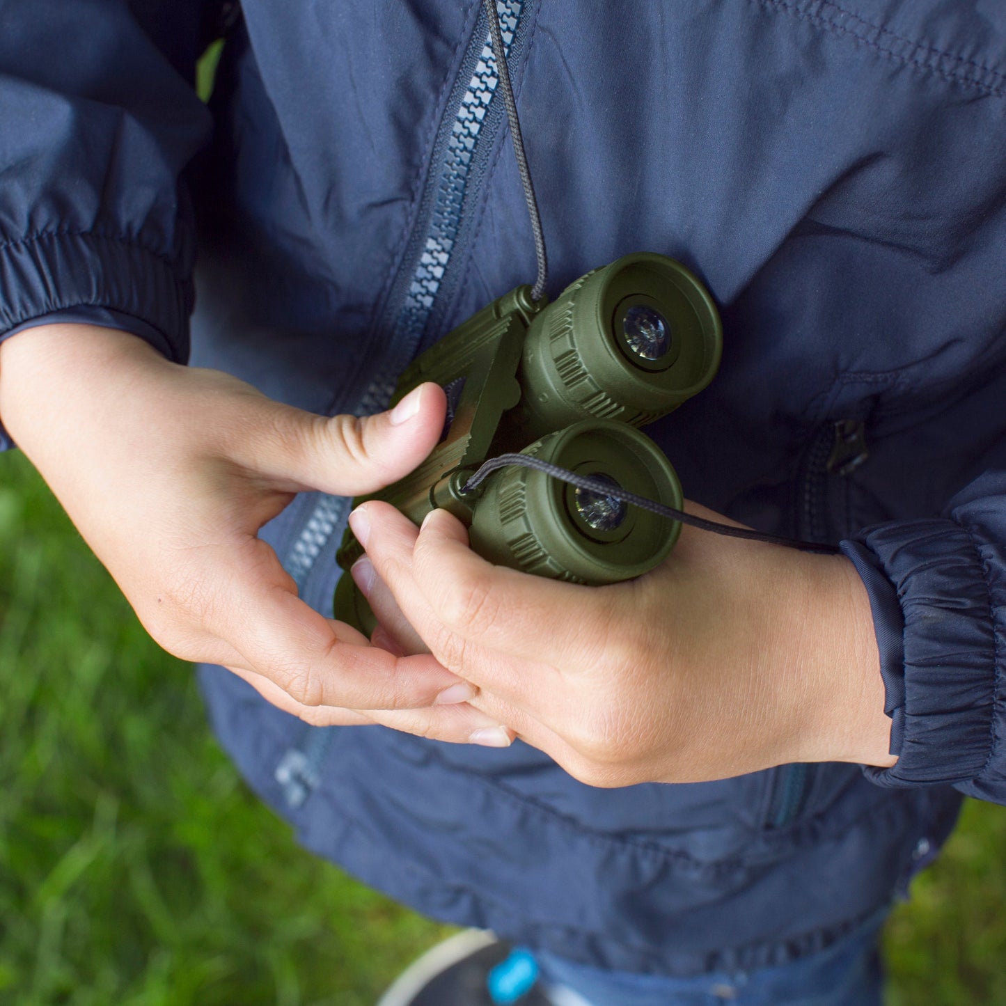 Olive binoculars held in hands, ready for viewing