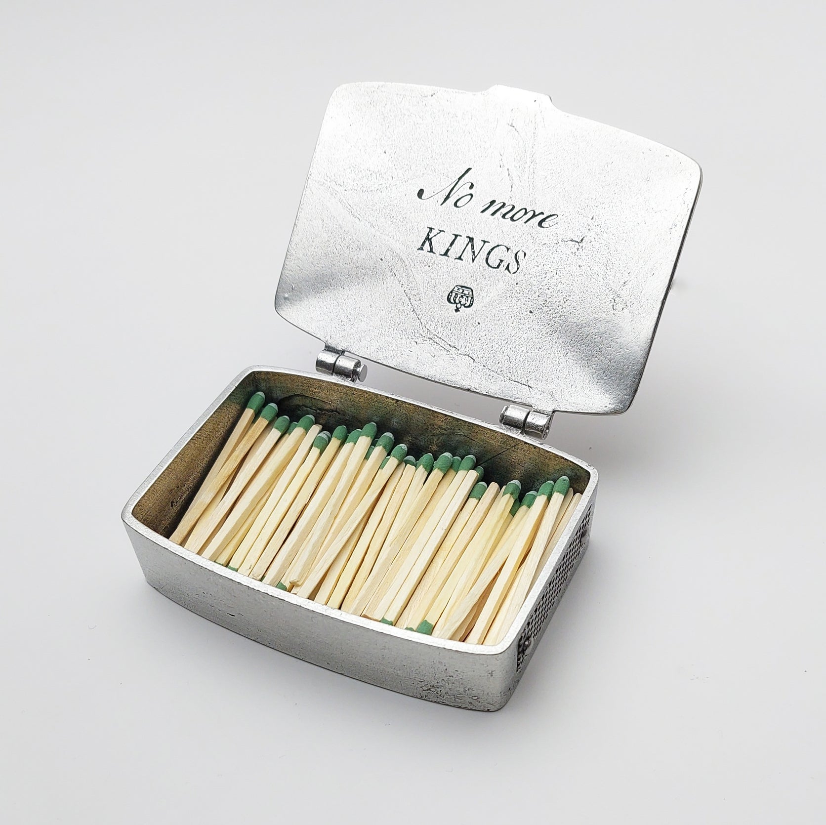 Open metal matchbox tin with wooden matches; lid reads 'More Kinds'