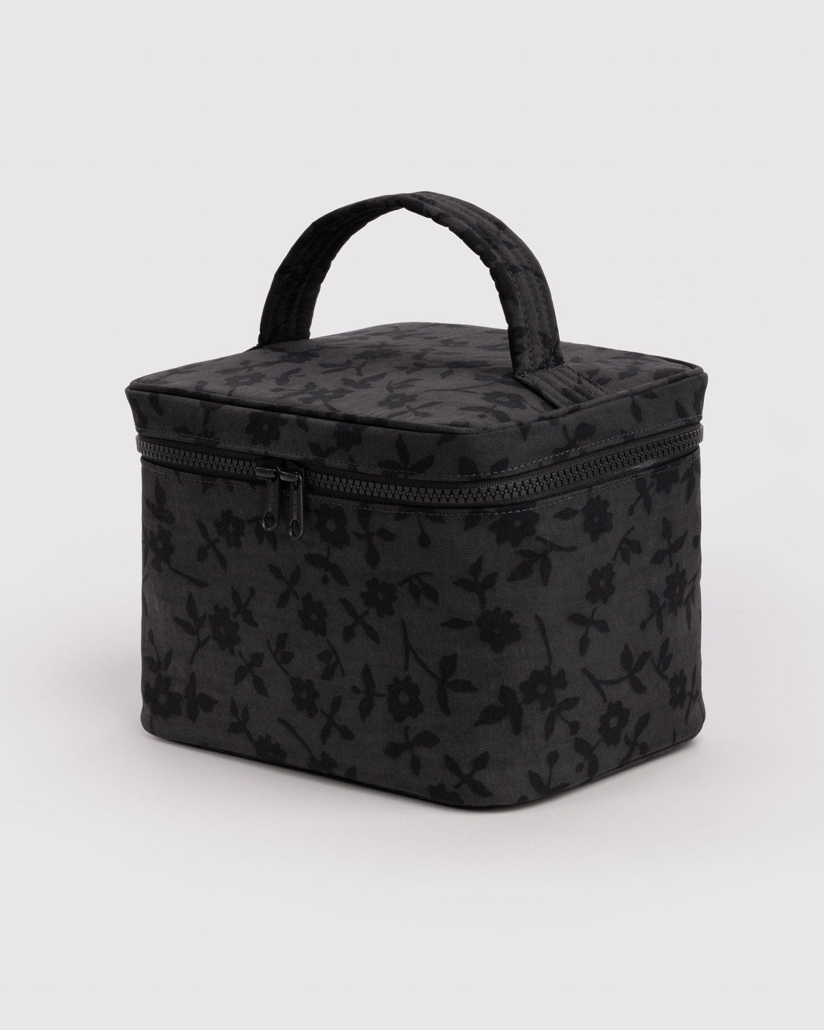 Large cosmetic case in dark charcoal floral print with top handle and zip closure.