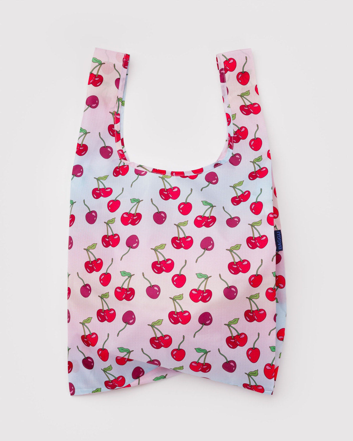 Reusable tote bag in pale pink with repeating cherry print and short U-shaped handles.