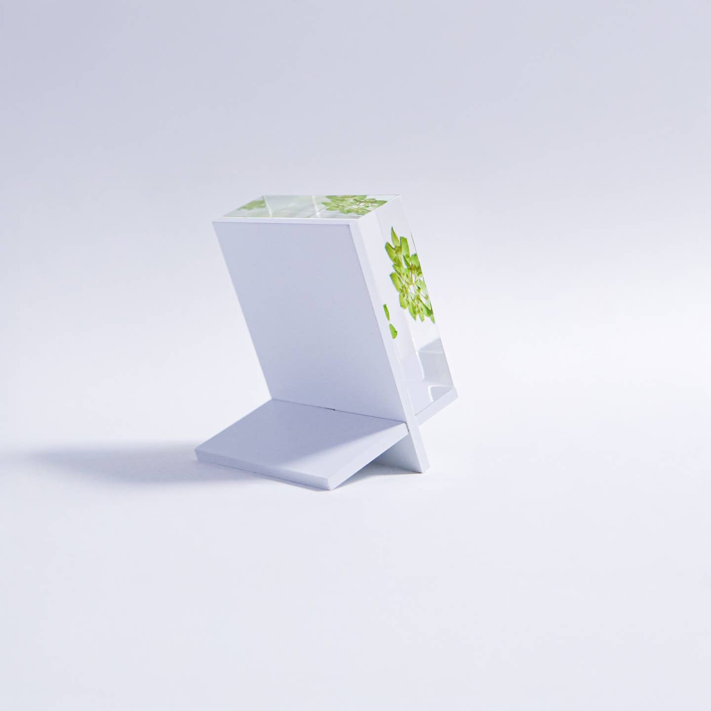 White tile stand with angled open frame showing green leaf design