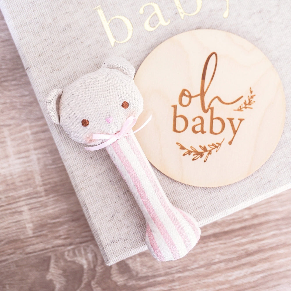 Ted stick rattle with bear head, pink-striped handle, gray tag and 'oh baby' patch
