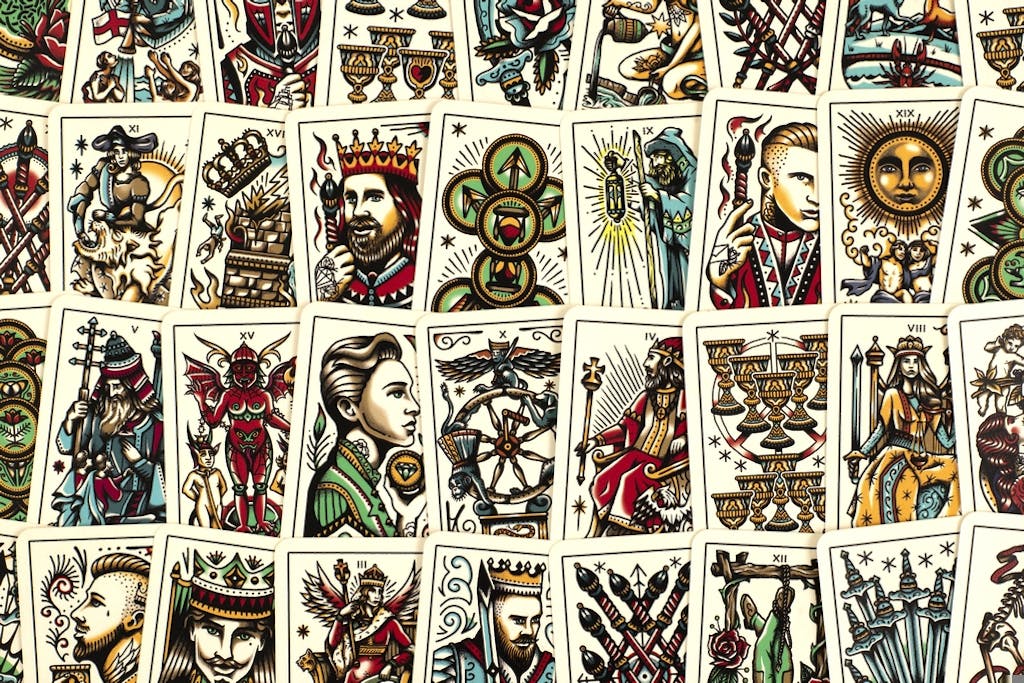 Tattoo tarot mini deck cards showing ornate illustrated faces, symbols, and suits