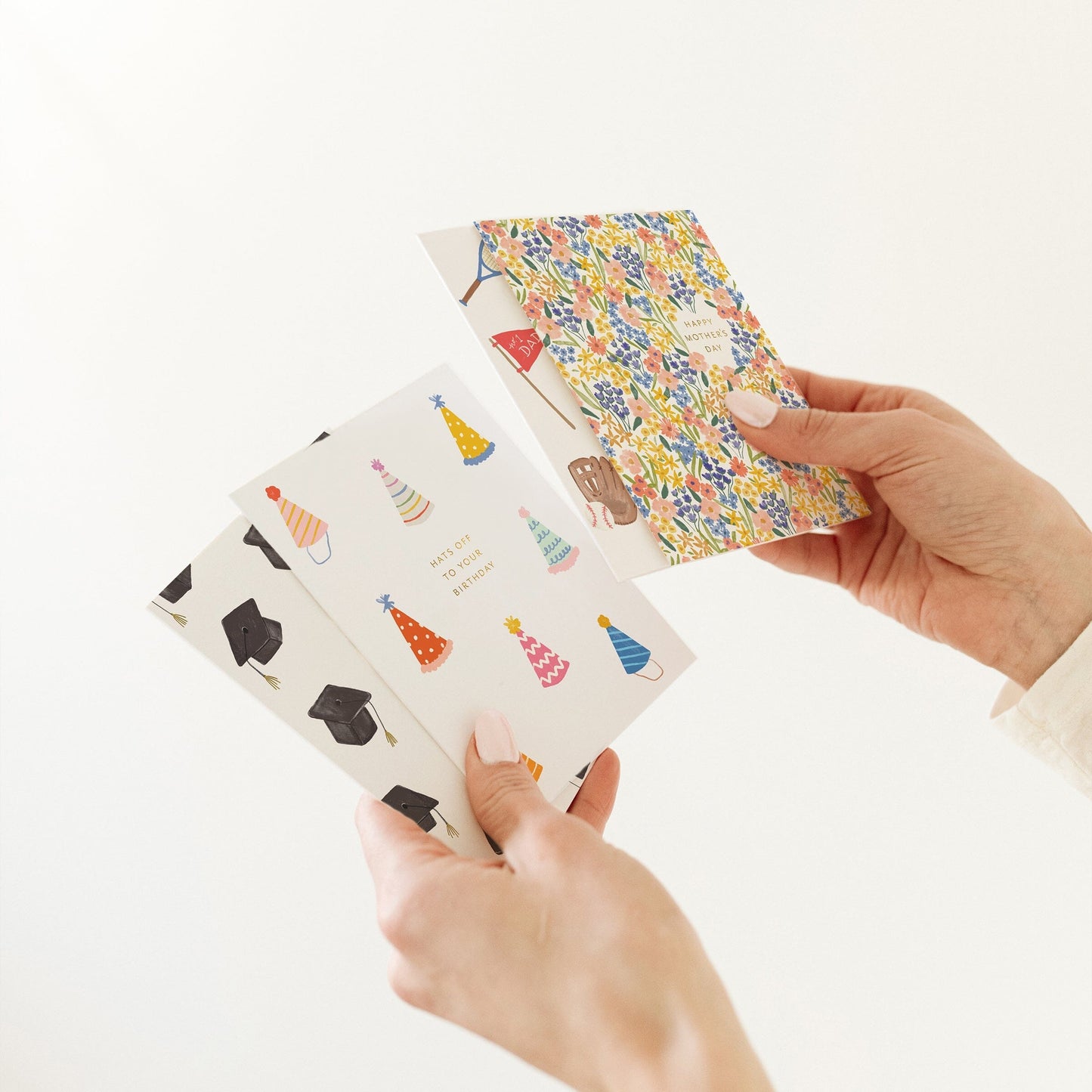 Greeting cards with colorful party hat prints, held in hands with one card open.
