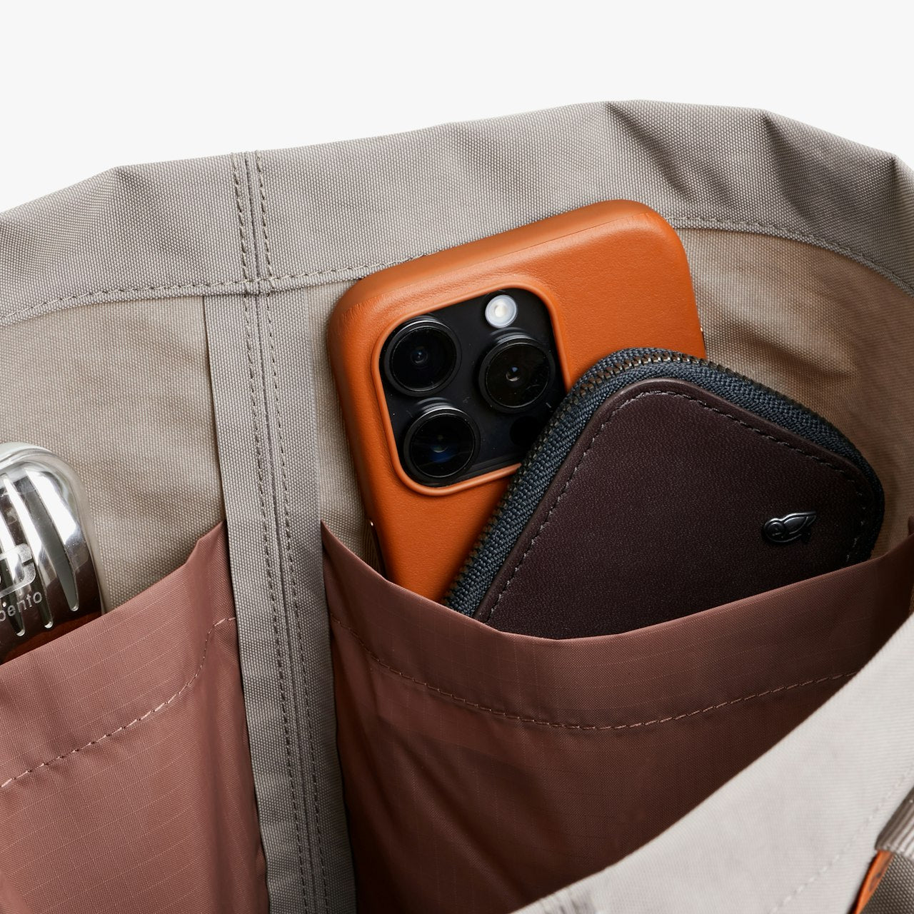 Gray tote bag interior organizer pocket with brown lining holding a phone