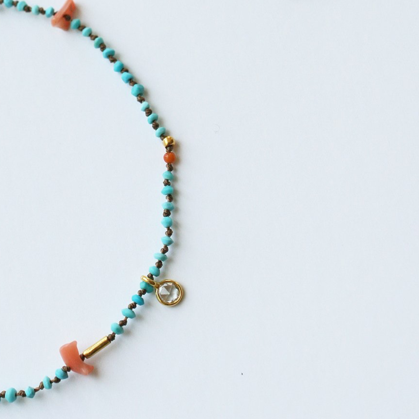 Turquoise beaded bracelet detail with orange end cap and gold round charm clasp