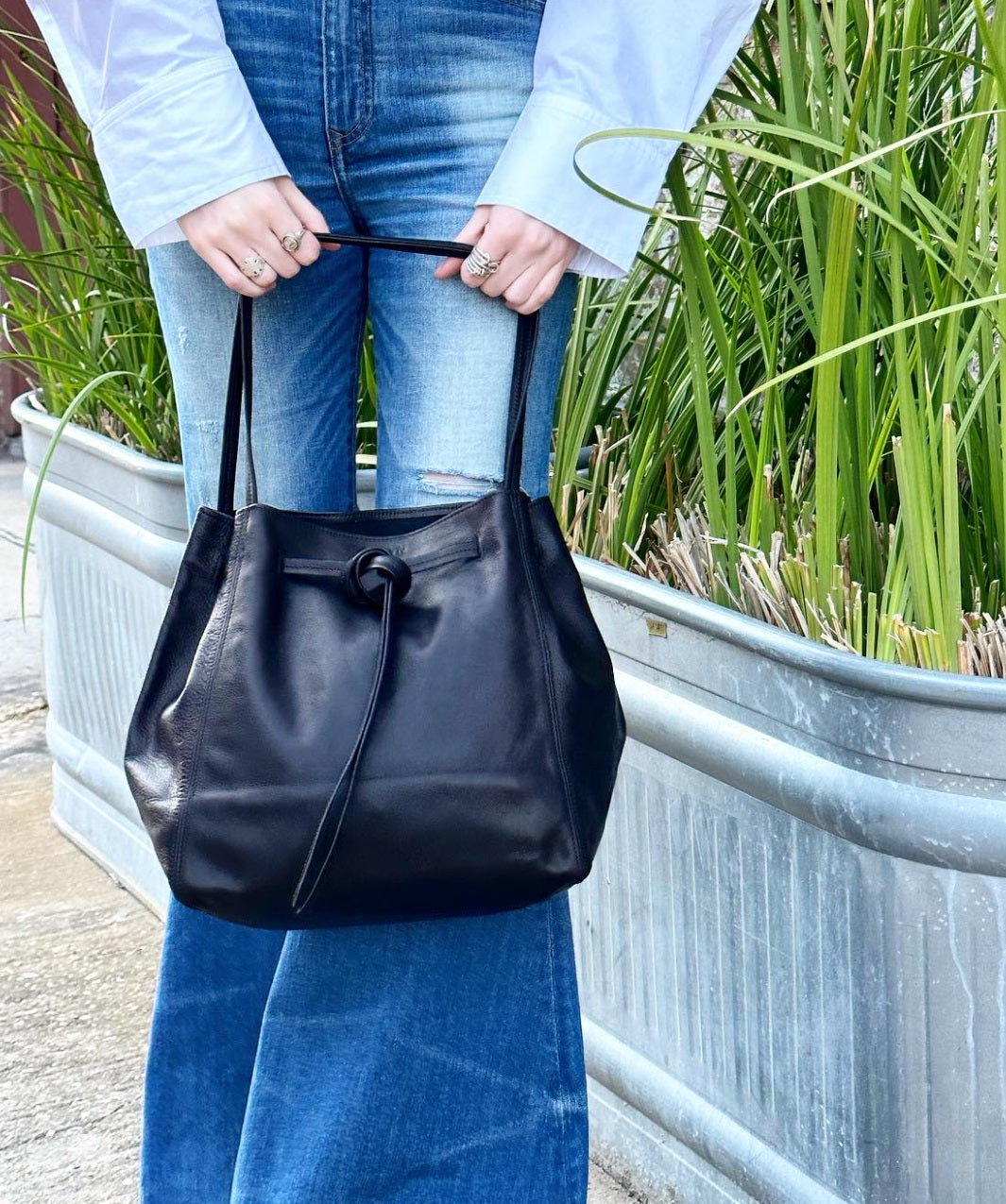 Black leather tote bag with drawstring closure and top handles