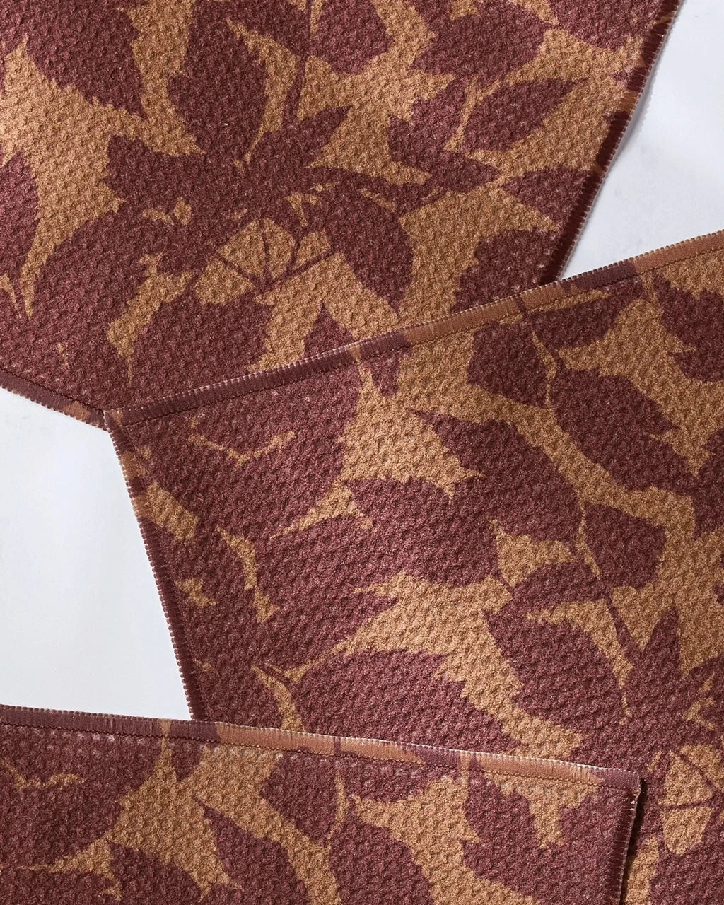 Rust brown leaf-pattern dishcloth with stitched edge and woven texture, close-up view