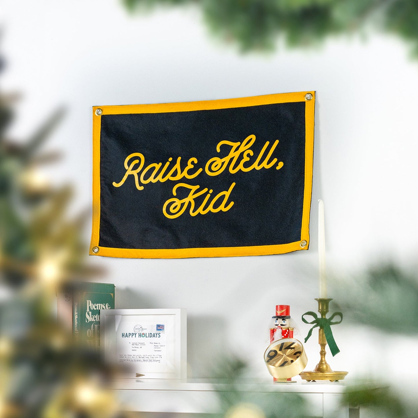 Outdoor-style camp flag on a pole, black with gold border and “Raise Hell, Kid” text.