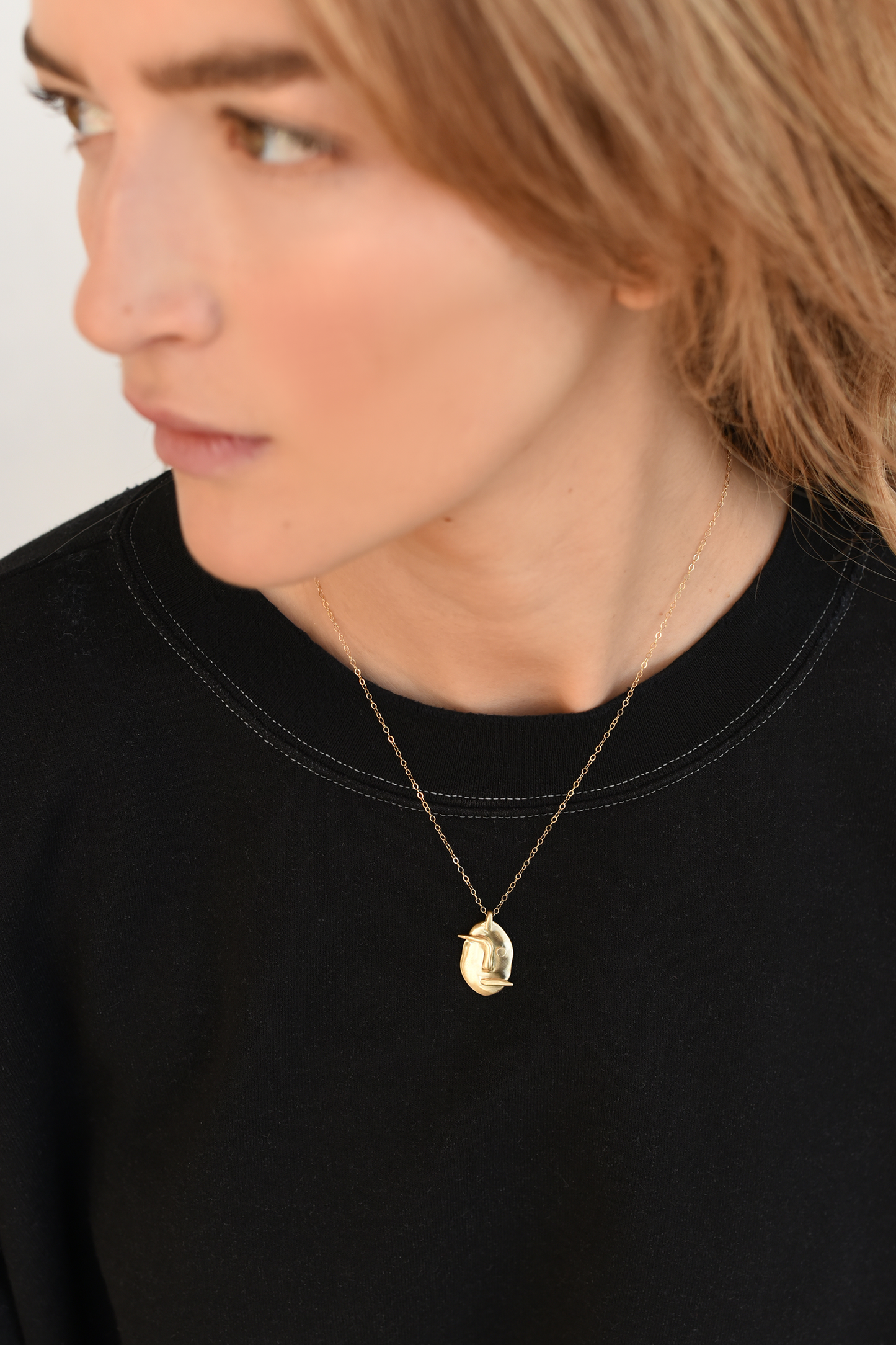 Brass face pendant necklace worn on neckline, small face charm on chain
