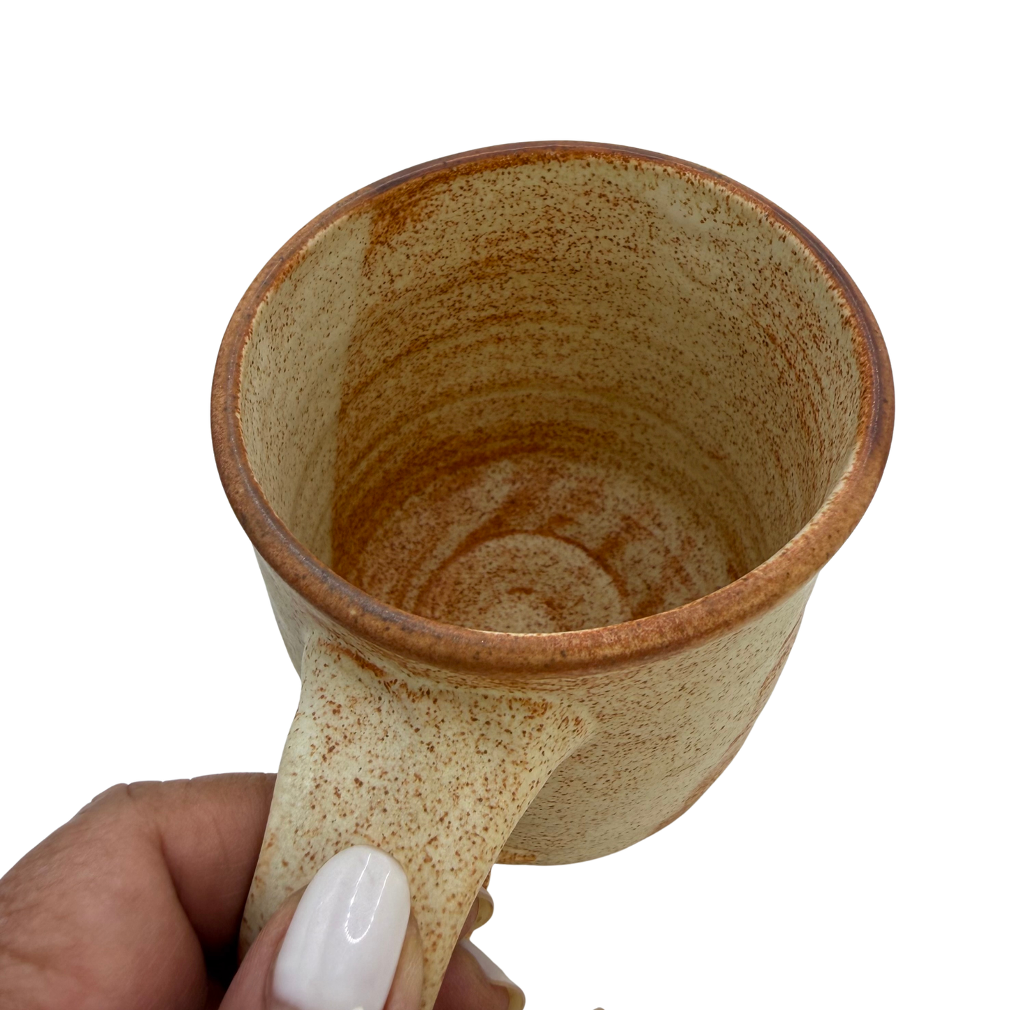 Two-tone amber speckled ceramic mug held by a hand, open top visible