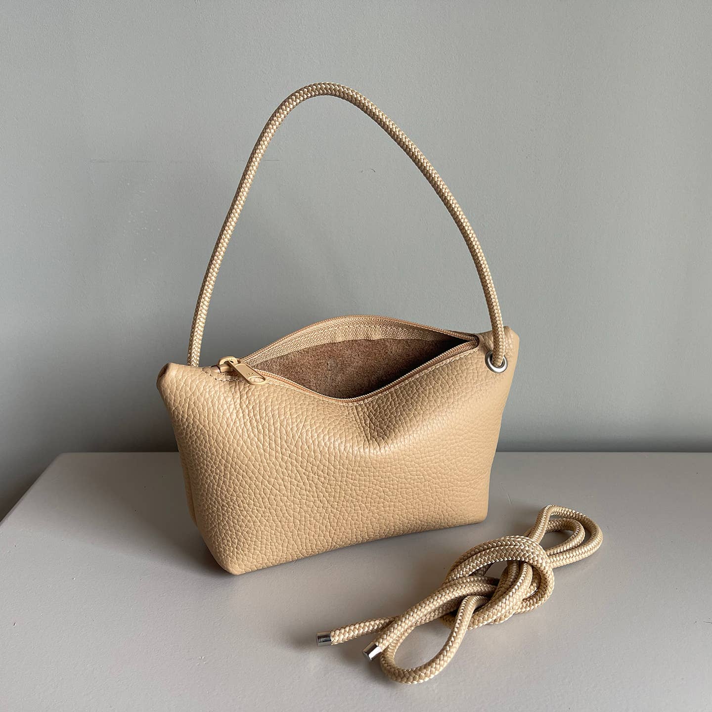 Champagne cord pouch with taupe braided handle, open top showing lining.
