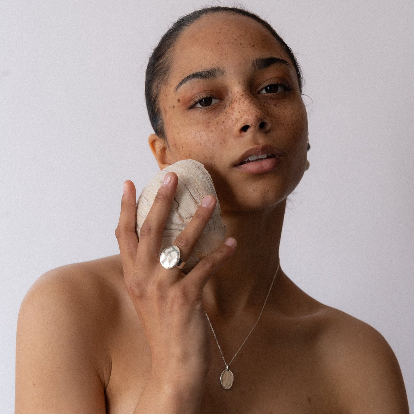 Silver hammered round-face ring on finger, shown in front pose