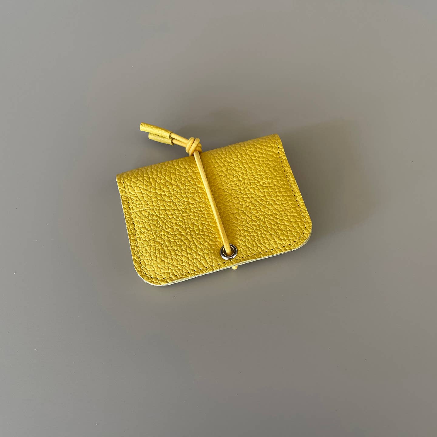 Yellow leather mini wallet with knot closure and metal eyelet button