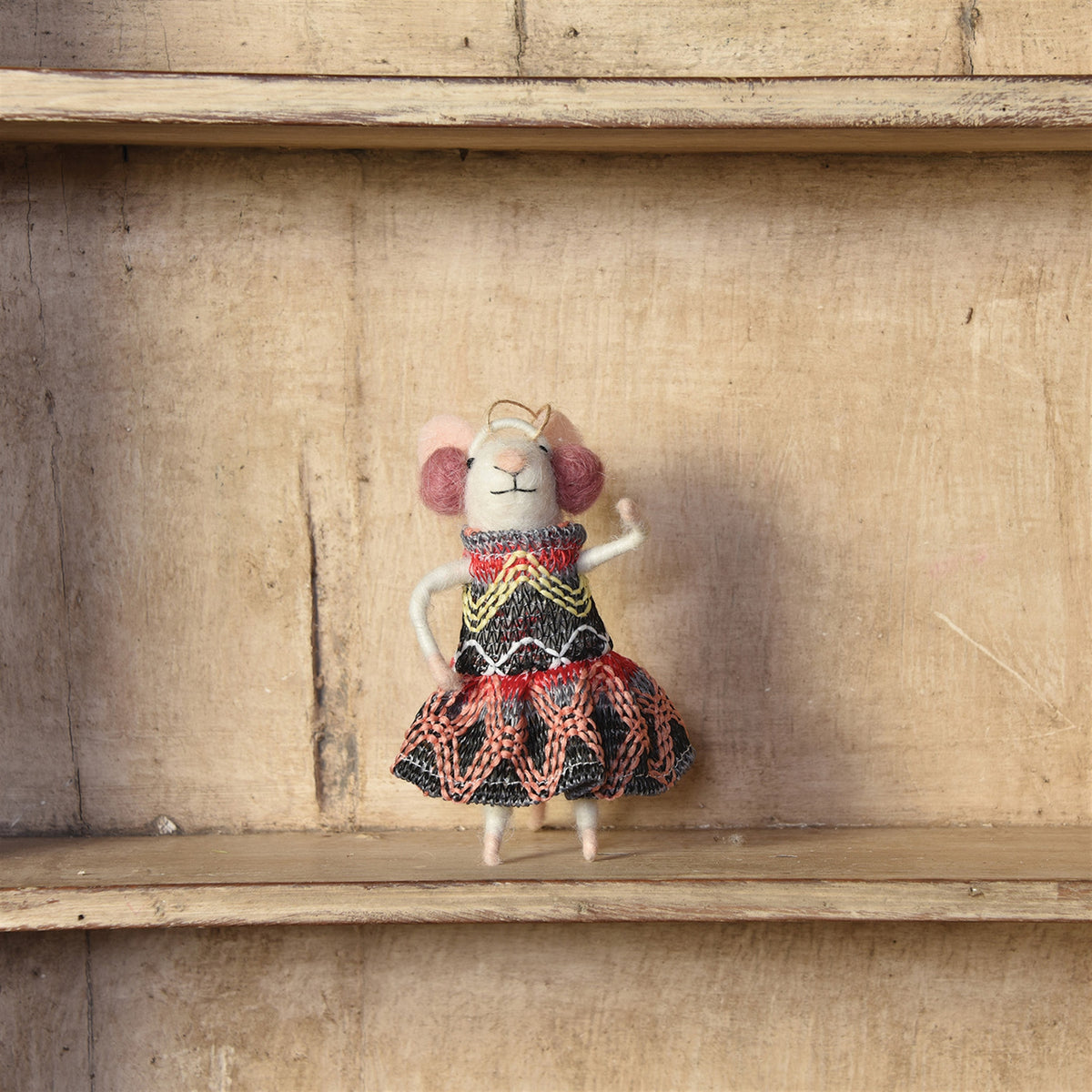 Felt mouse doll with closed eyes, wearing patterned red-black knit dress and striped sweater.