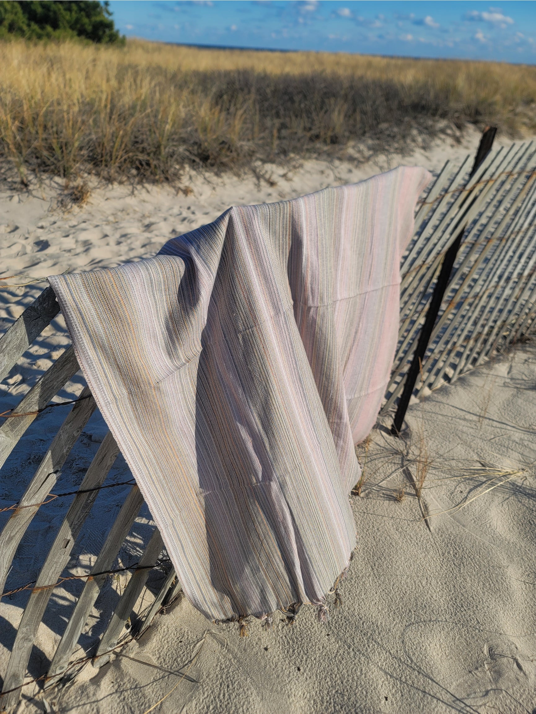 Gray striped throw blanket with fringed ends, draped