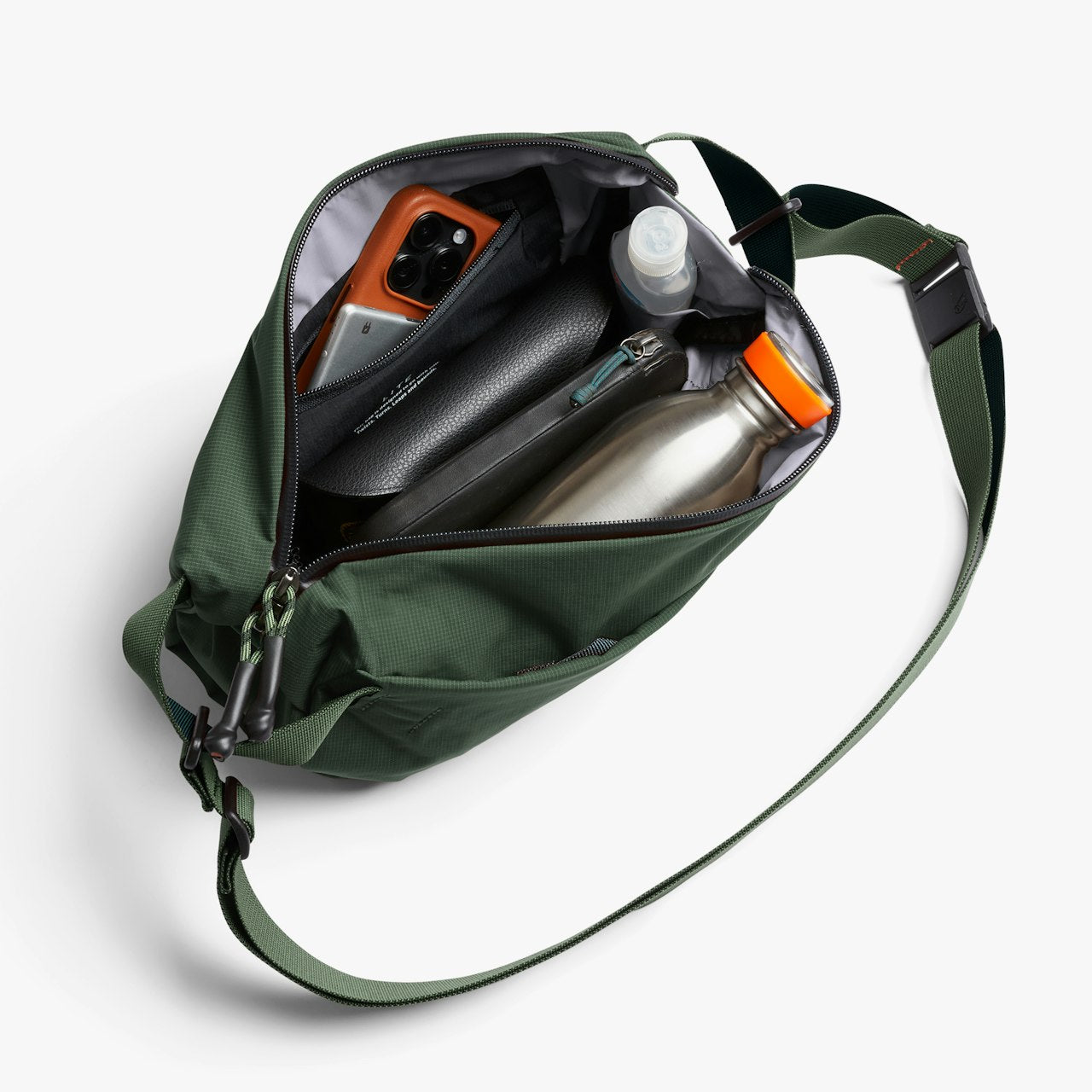 Open green sling bag with zipper opening, interior pockets, and adjustable strap