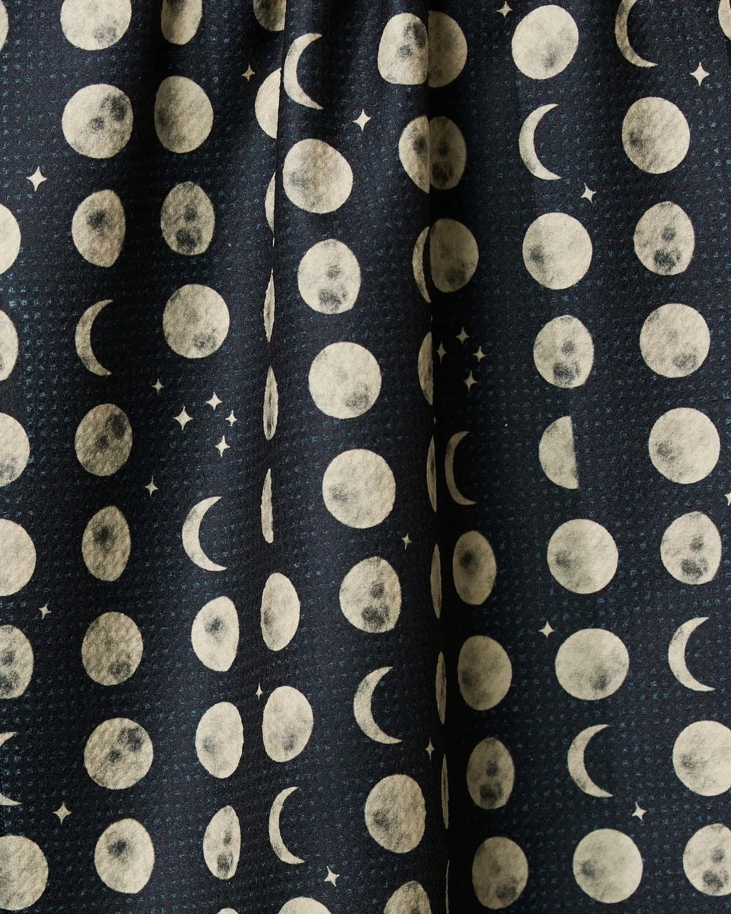 Kitchen tea towel fabric close-up with white moons and dot pattern on dark navy