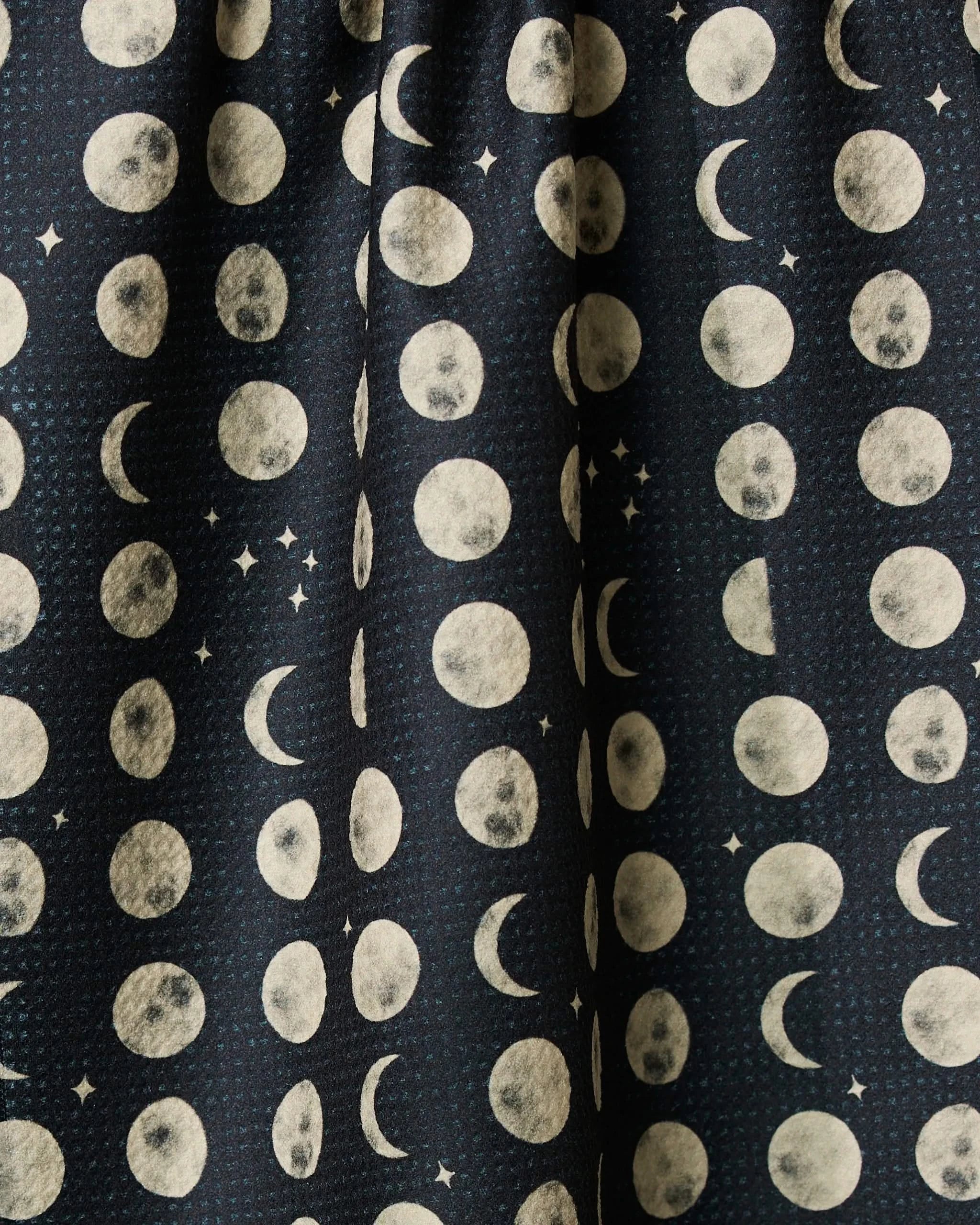 Kitchen tea towel fabric close-up with white moons and dot pattern on dark navy