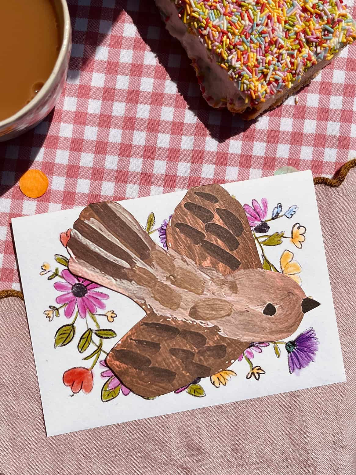 Greeting card with illustrated brown bird on white front, colorful flowers around