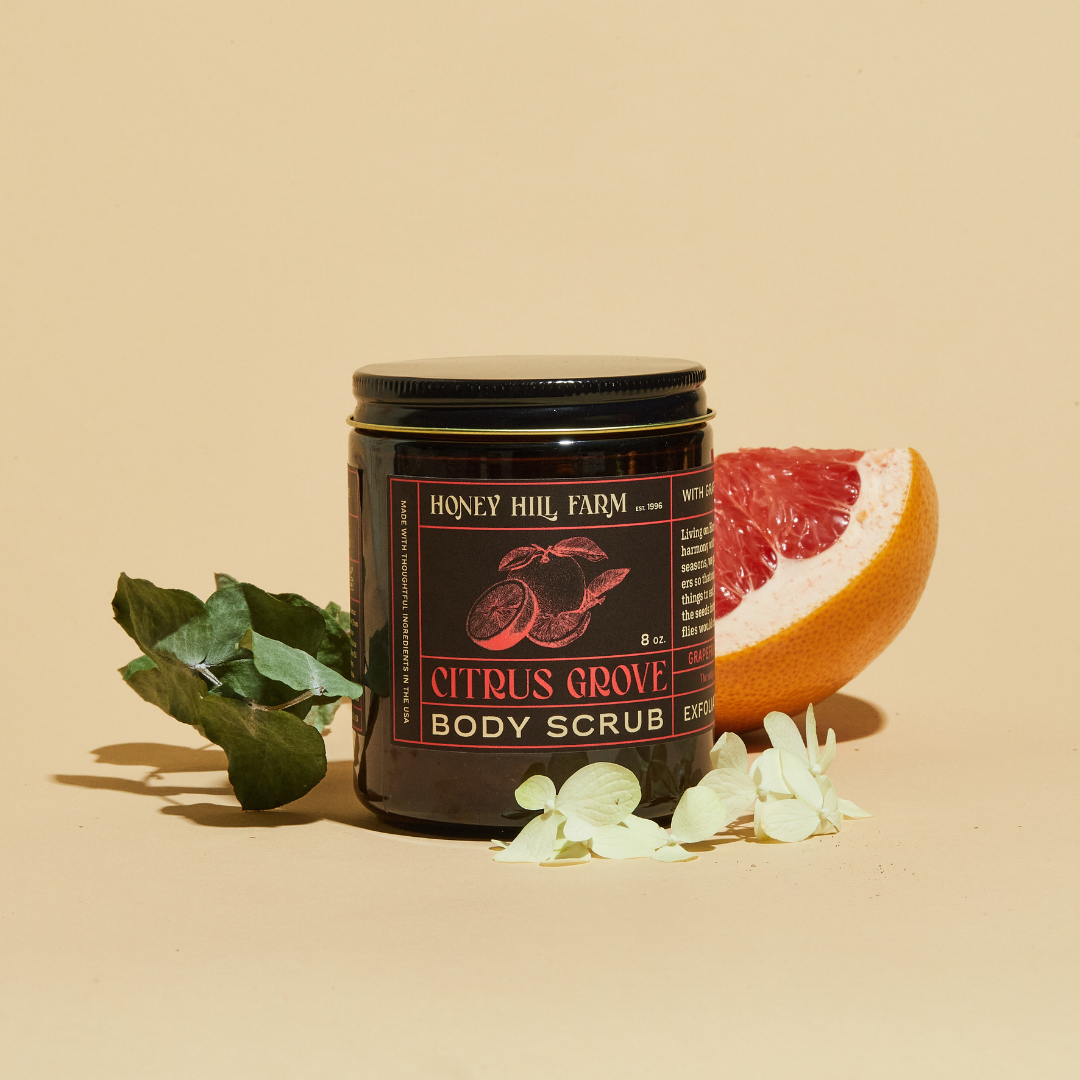 Citrus Grove body scrub jar with black lid, citrus fruit and leaves
