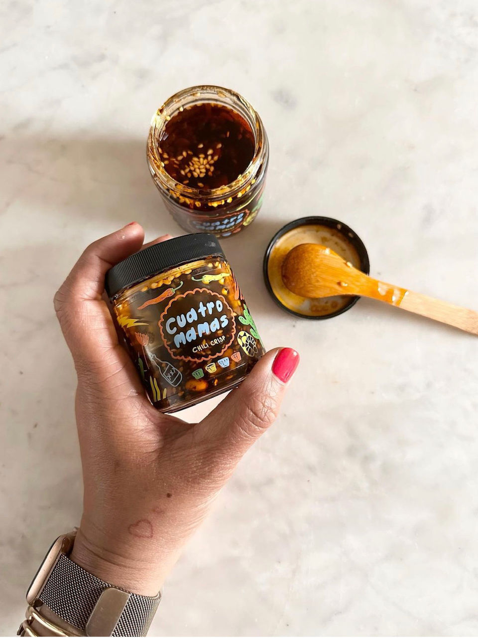 Chili crisp jar with black label, held in hand, mild chili crisp in open glass