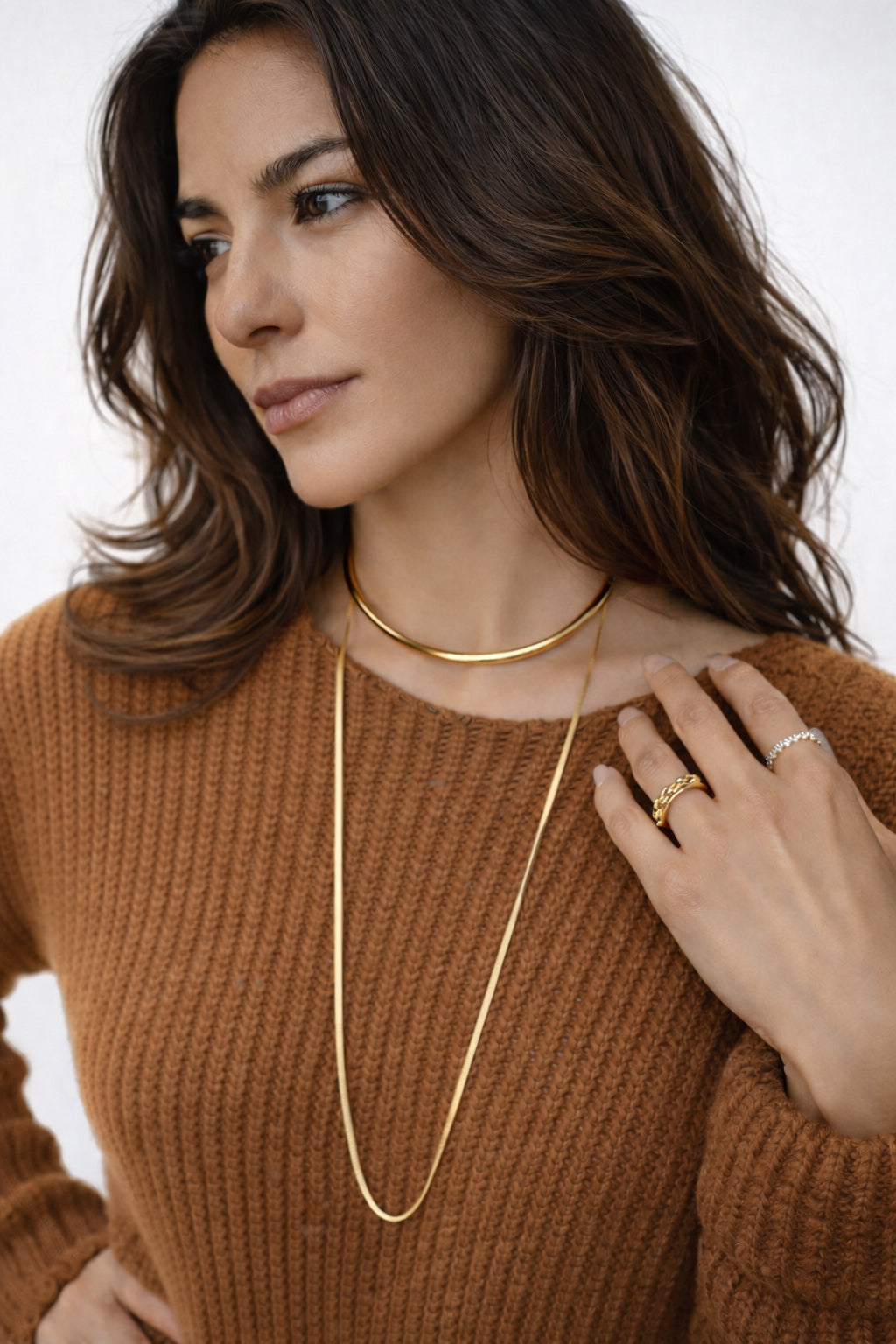Gold-tone layered chain necklace worn at the collar