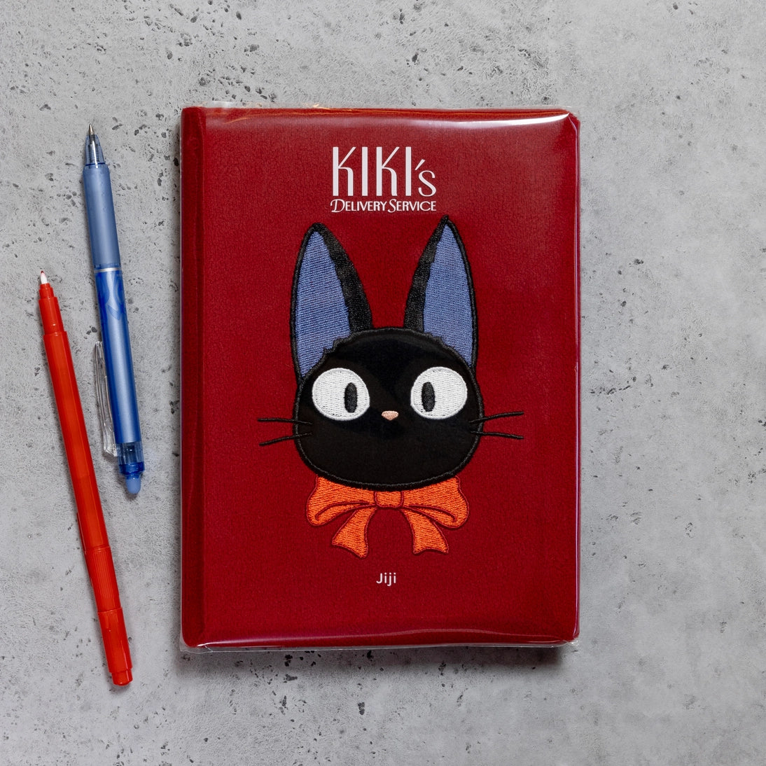 Red plush journal cover with Kiki's logo and Jiji black cat face