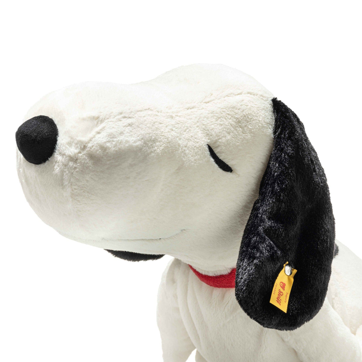 Snoopy plush face close-up, white fur with black ears and red collar