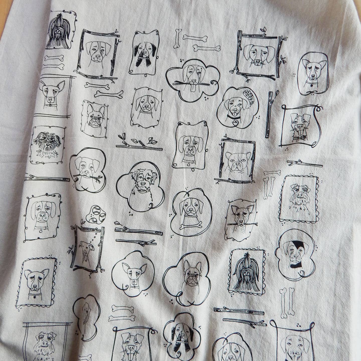 Dog kitchen tea towel with repeating line-drawn dog portraits and kitchen icons.