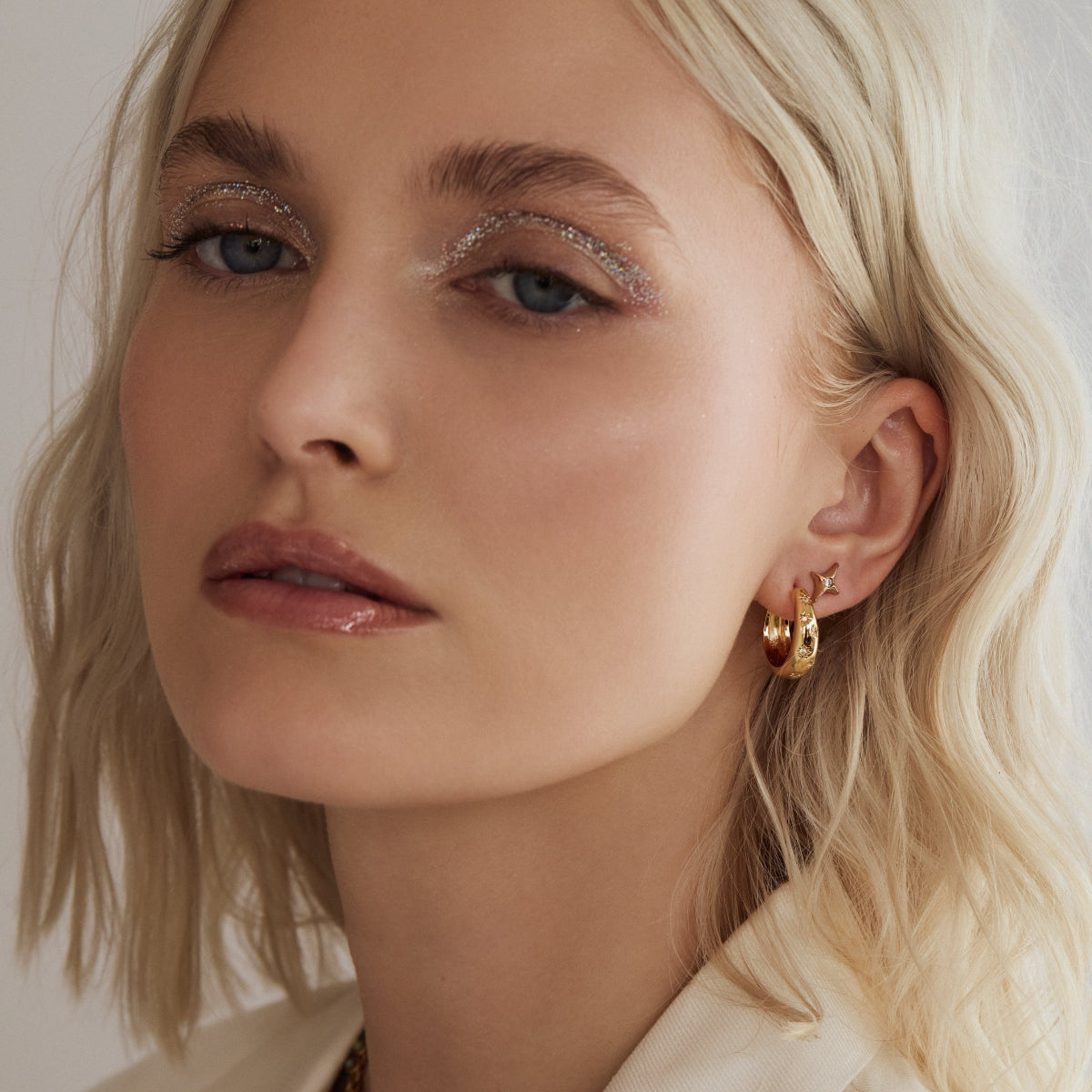 Gold-tone hoop earrings with small star crystals on ear