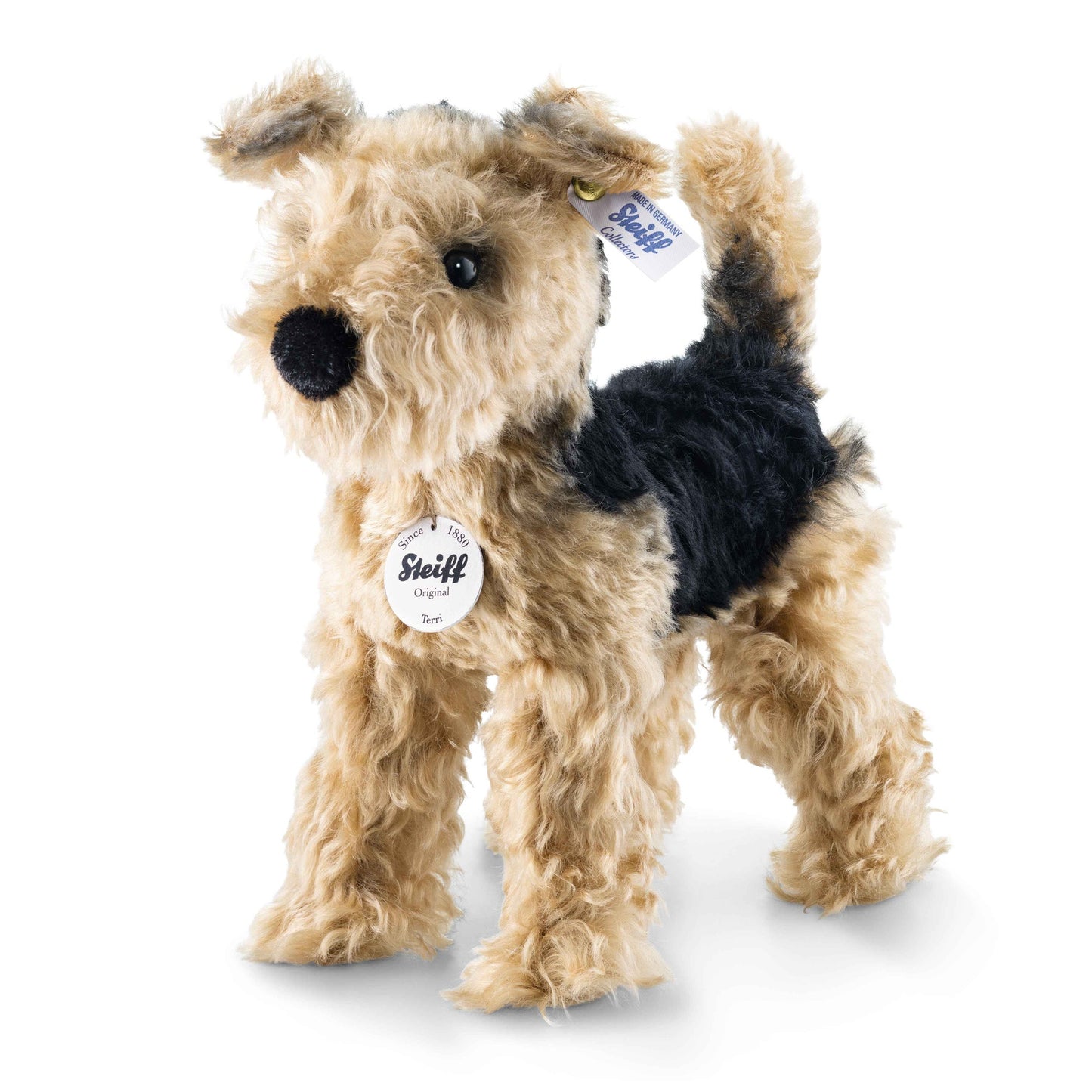 Tan plush terrier dog with black face patch and floppy ears, wearing Steiff tag